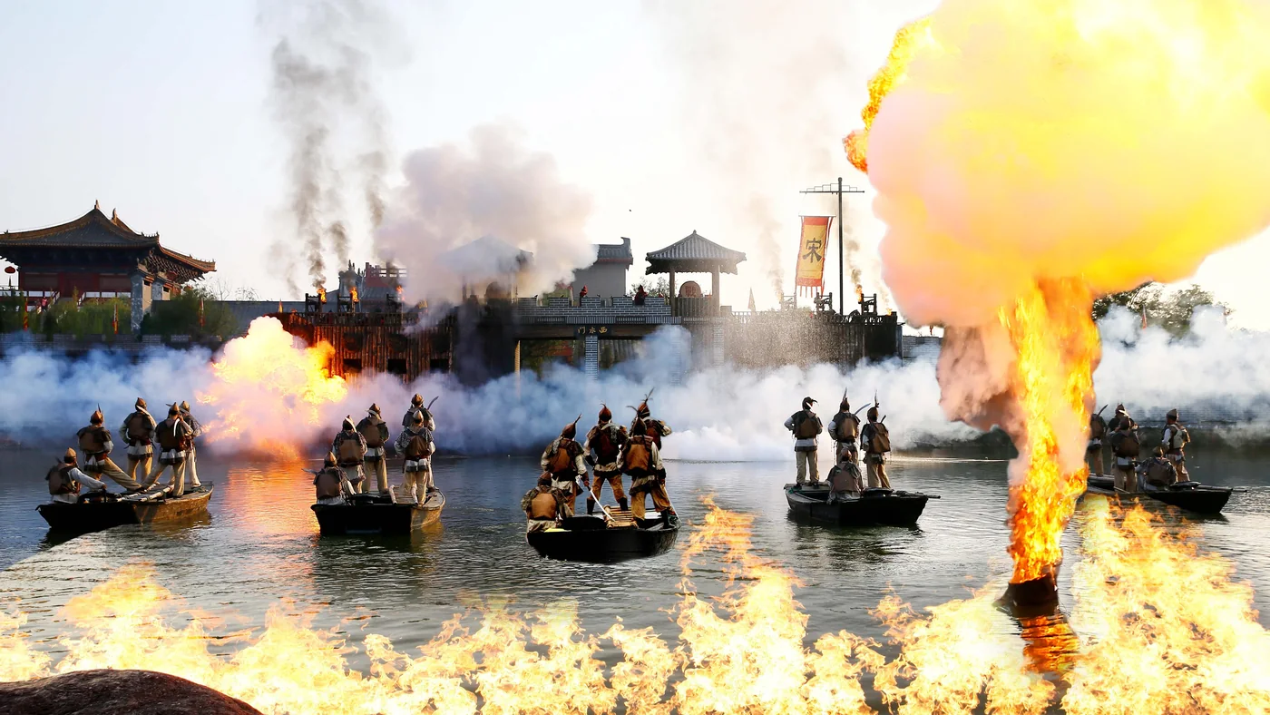 大宋·东京保卫战实景：水面战阵与火光特效铺开激烈场景，演员用攻城、威亚等表演讲述保卫东京的故事